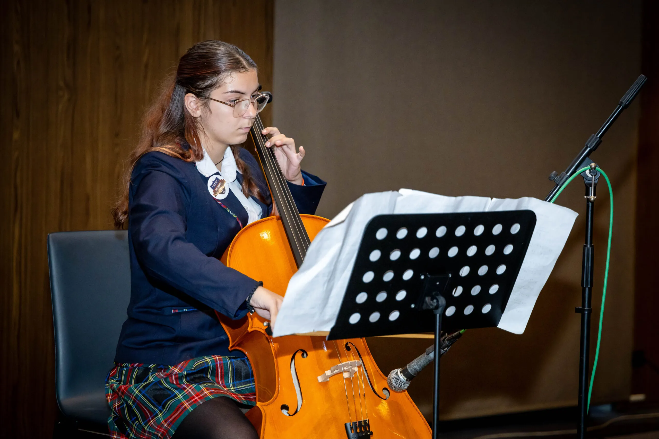 A student playing the cello at a school recital