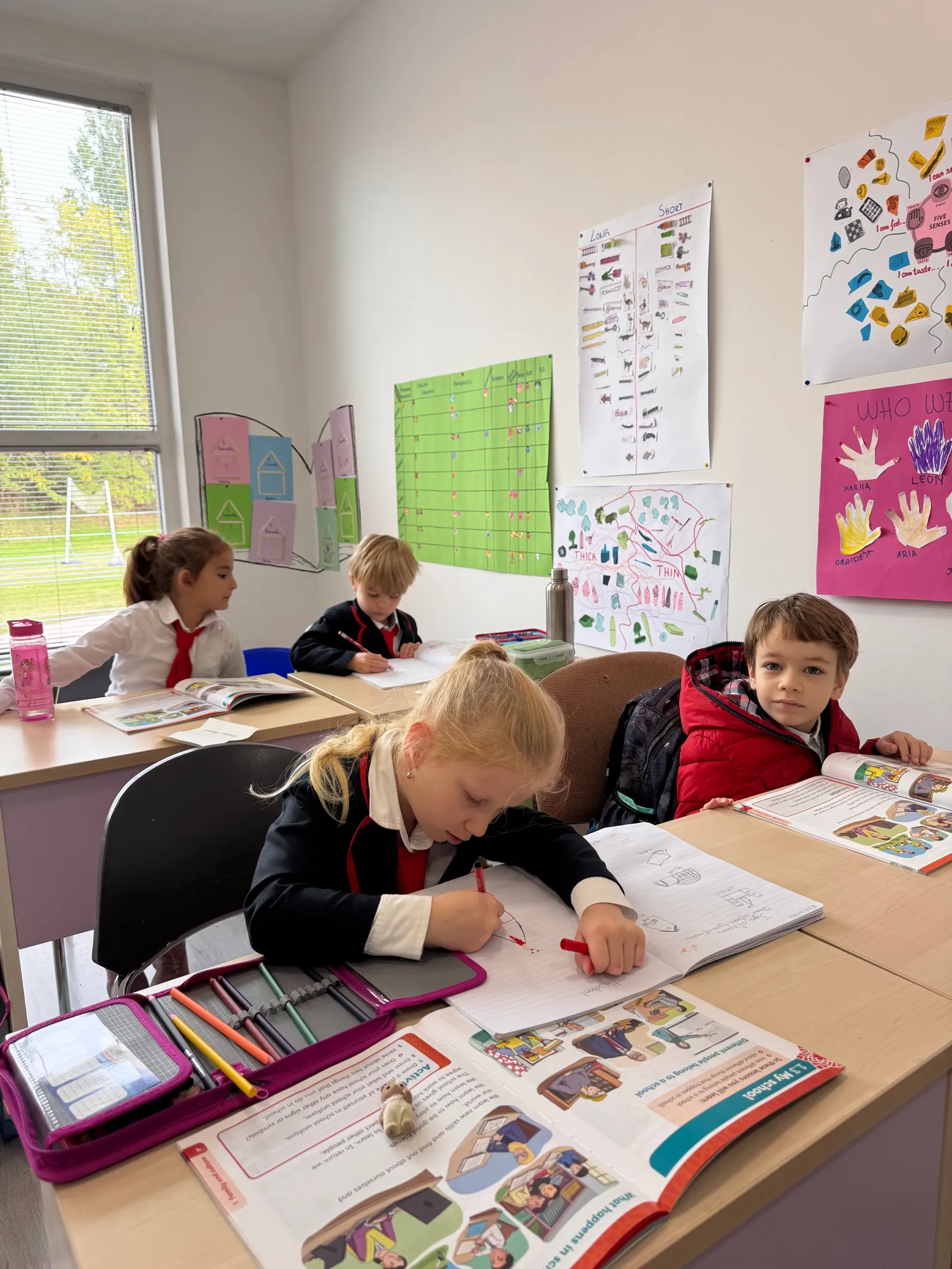 Wide view of the Grade 1 classroom, every desk busy under the wall charts