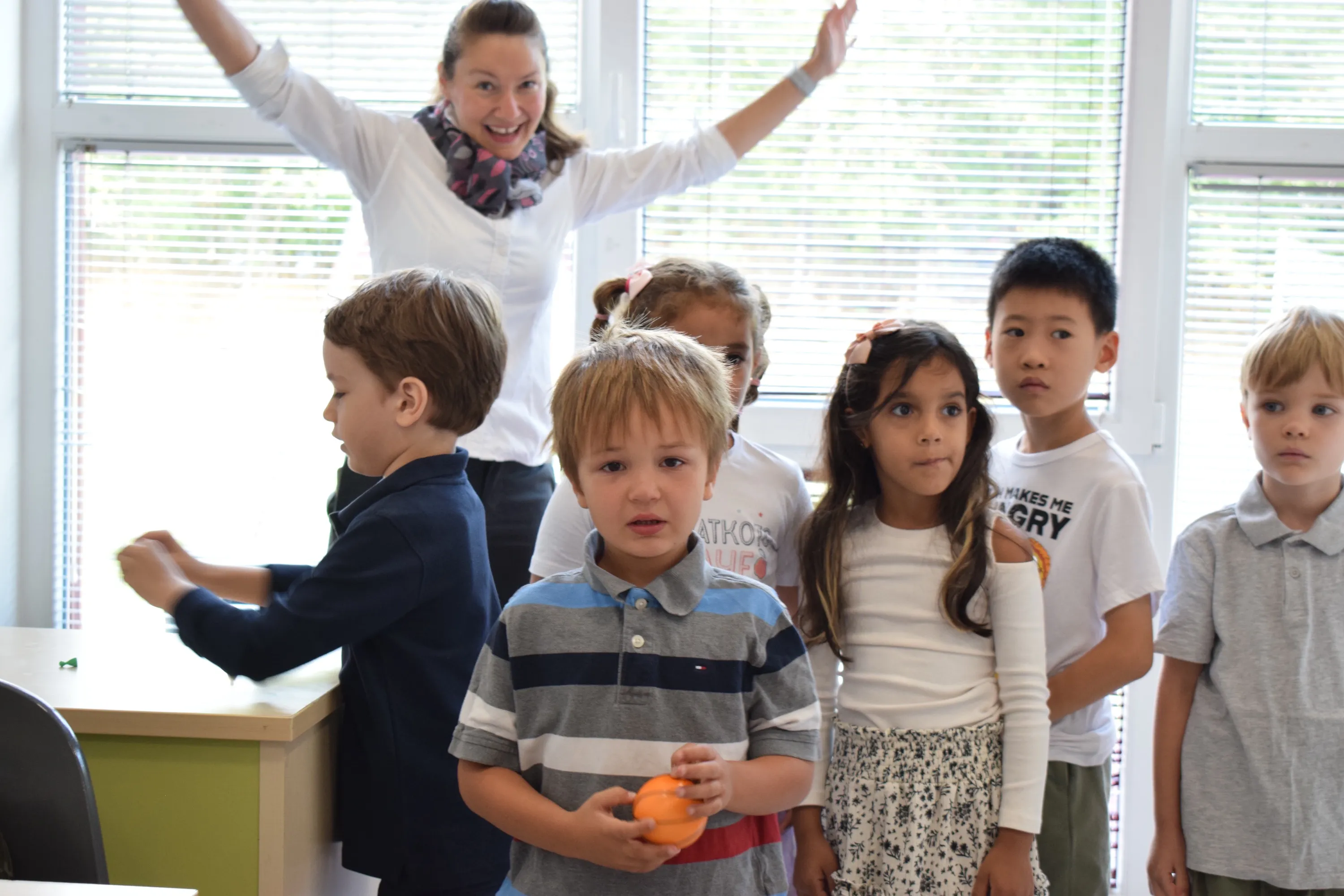 First graders lined up in their new classroom on the first day of school while their teacher cheers behind them