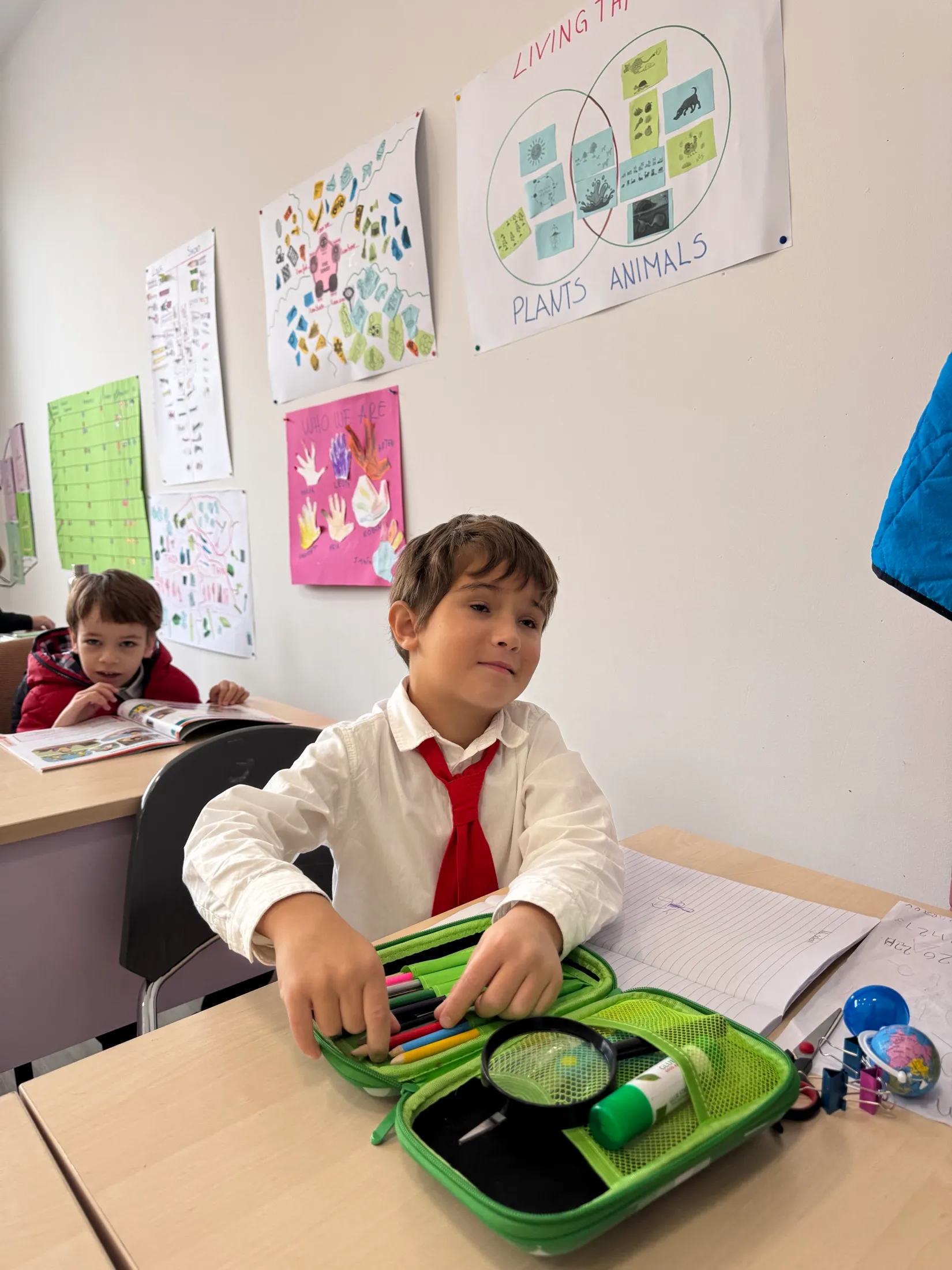 A first grader unpacks his pencil case — magnifying glass first