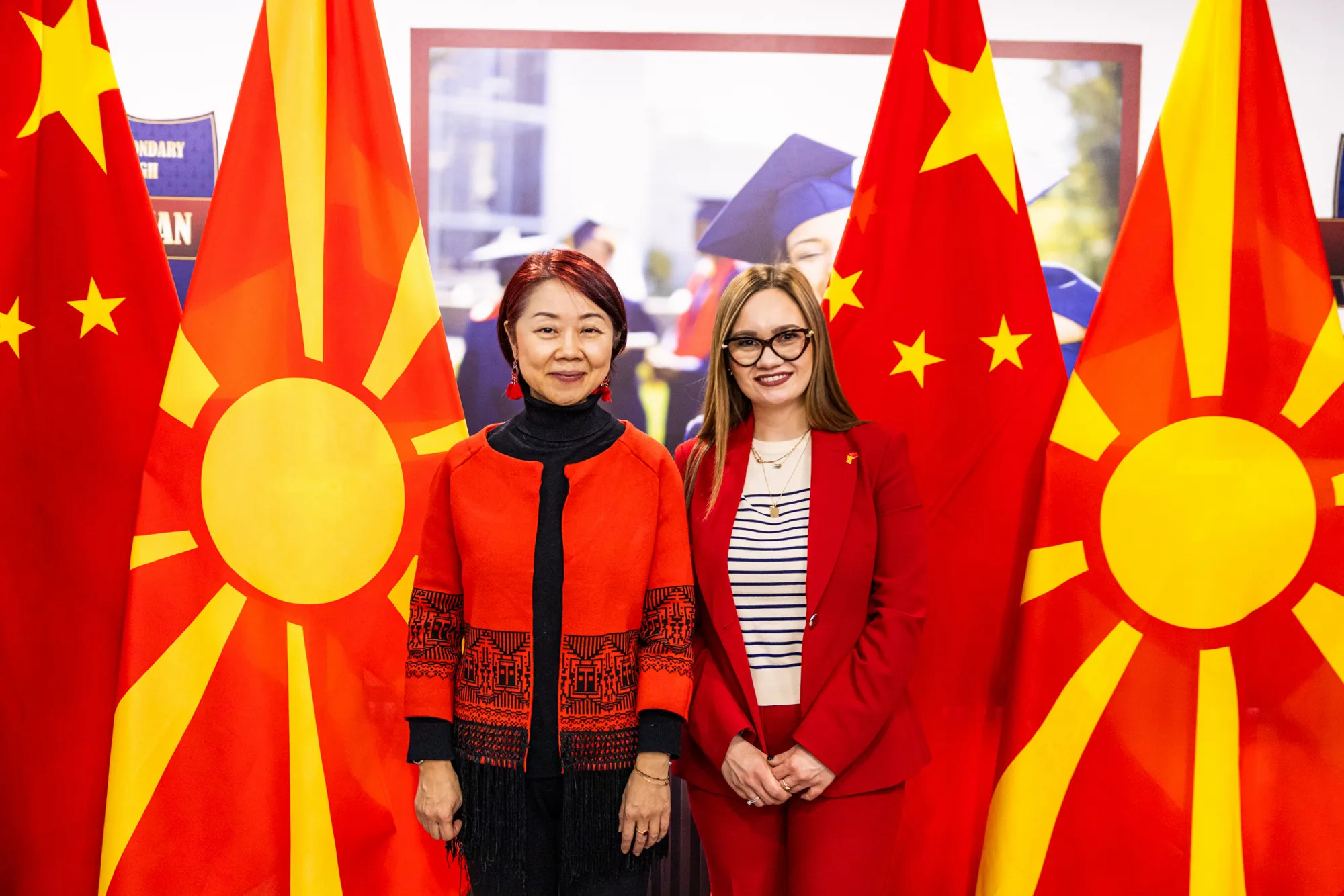 Guests standing between Macedonian and Chinese flags during a diplomatic visit to the school