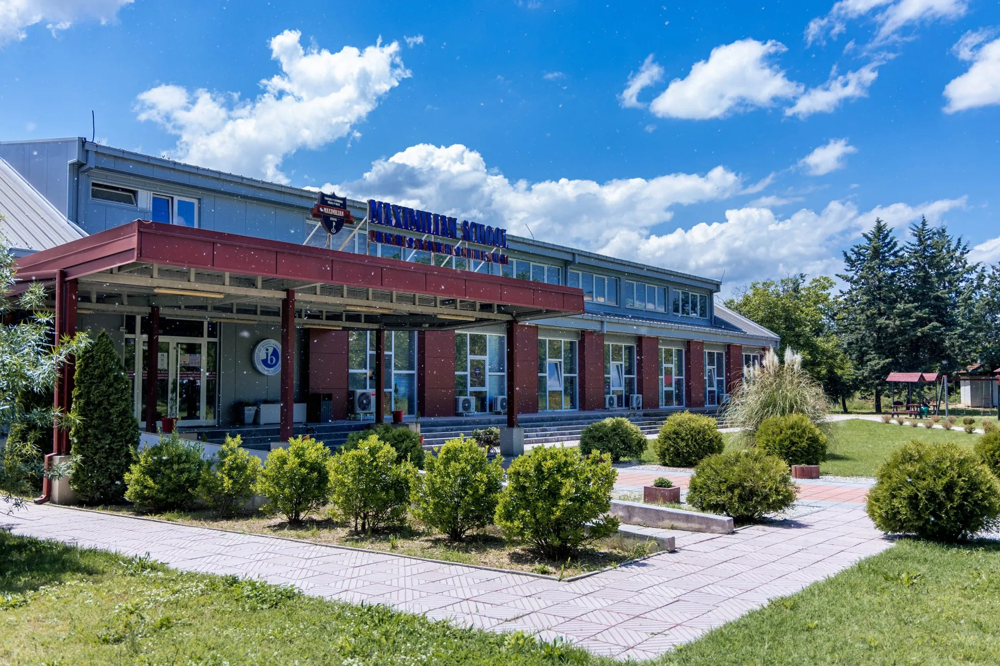 The Maximilian School building with its signage under a blue sky