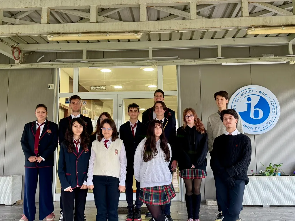 High school students in uniform in front of the school entrance with the IB World School sign