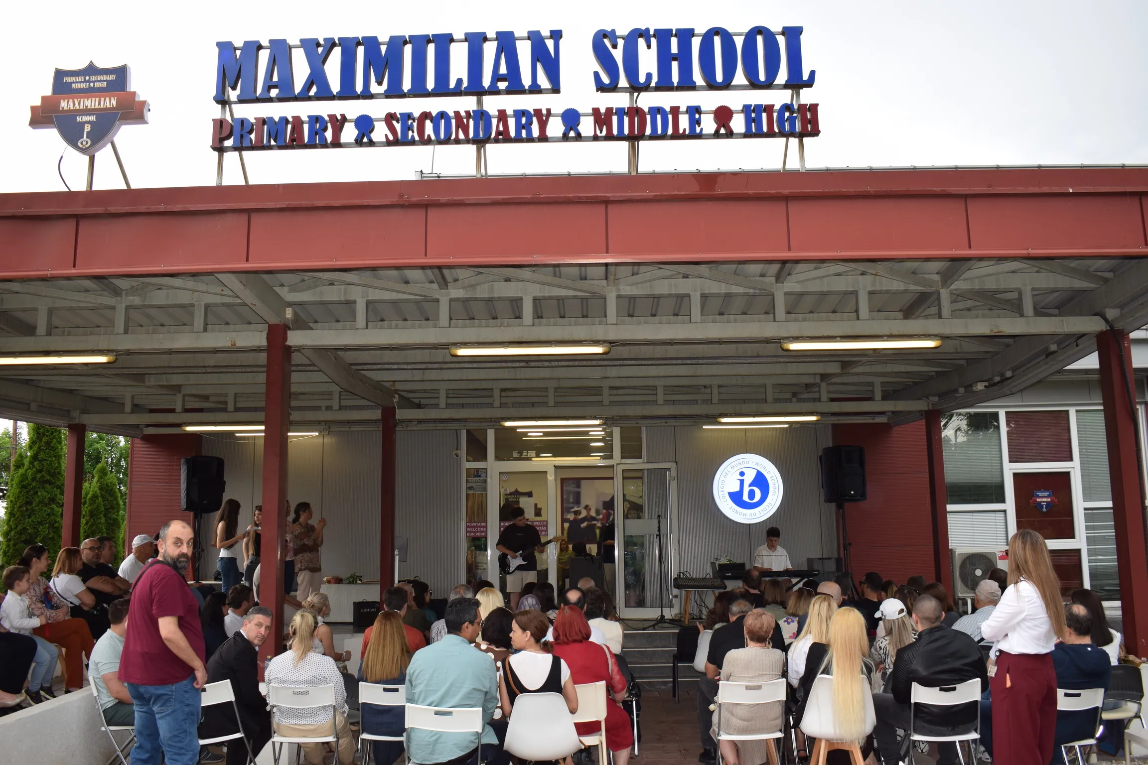 Families gathered in front of the Maximilian School building at a school celebration